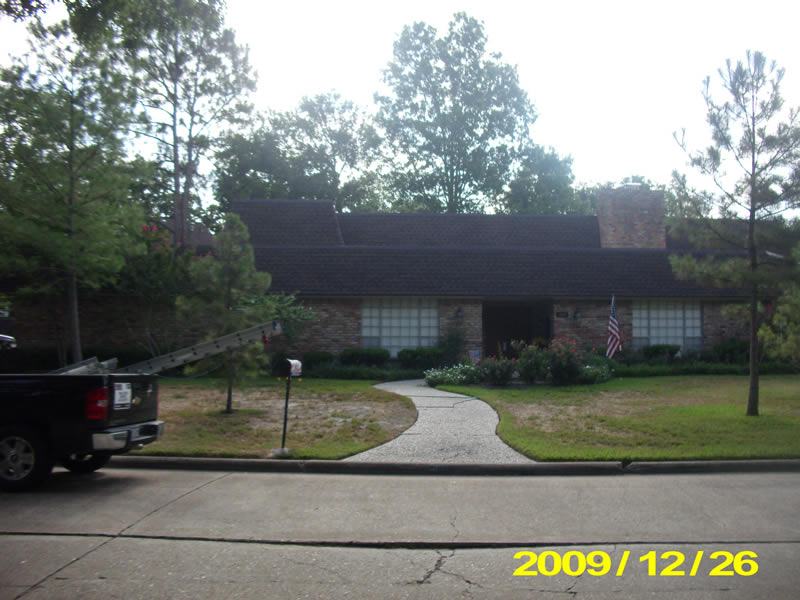 A house with a driveway and trees in the background