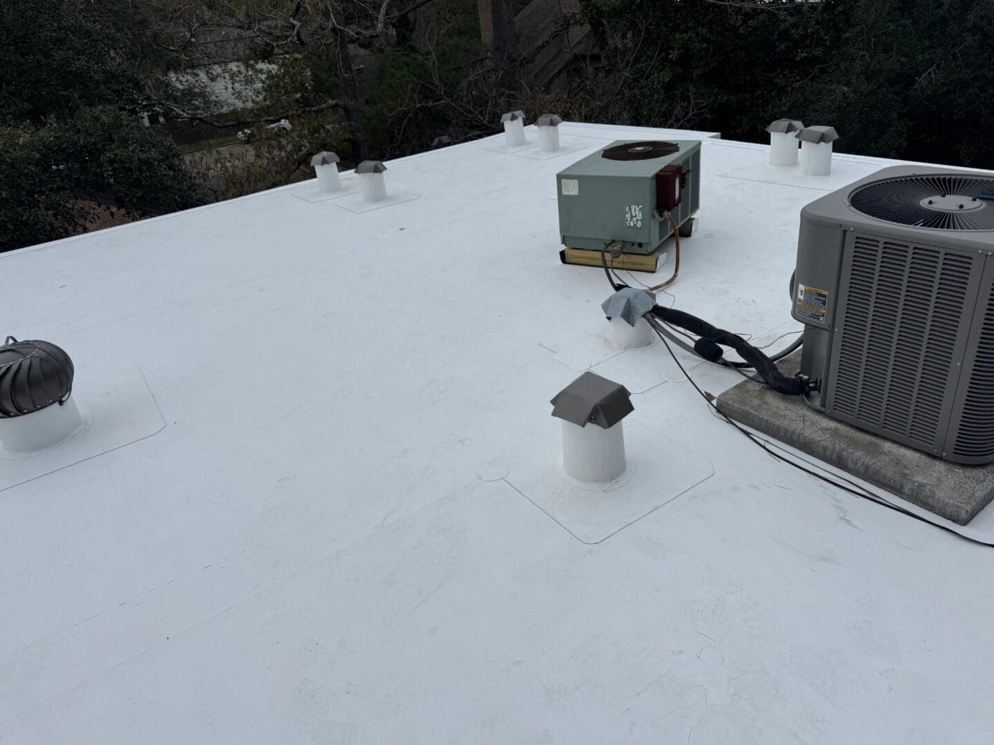 A flat commercial roof features a clean white membrane with installed HVAC units and roof vents completed through professional commercial roofing services.