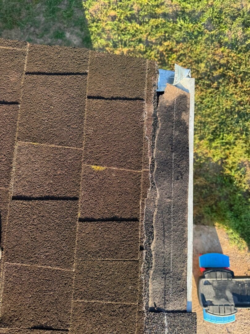Damaged shingles along a roof edge reveal an area requiring professional residential roof repair services.